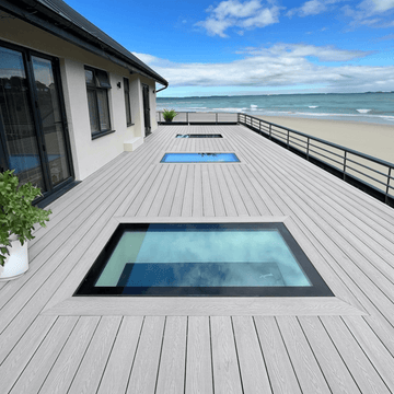 Light grey composite decking board on a beachside deck with glass skylights.