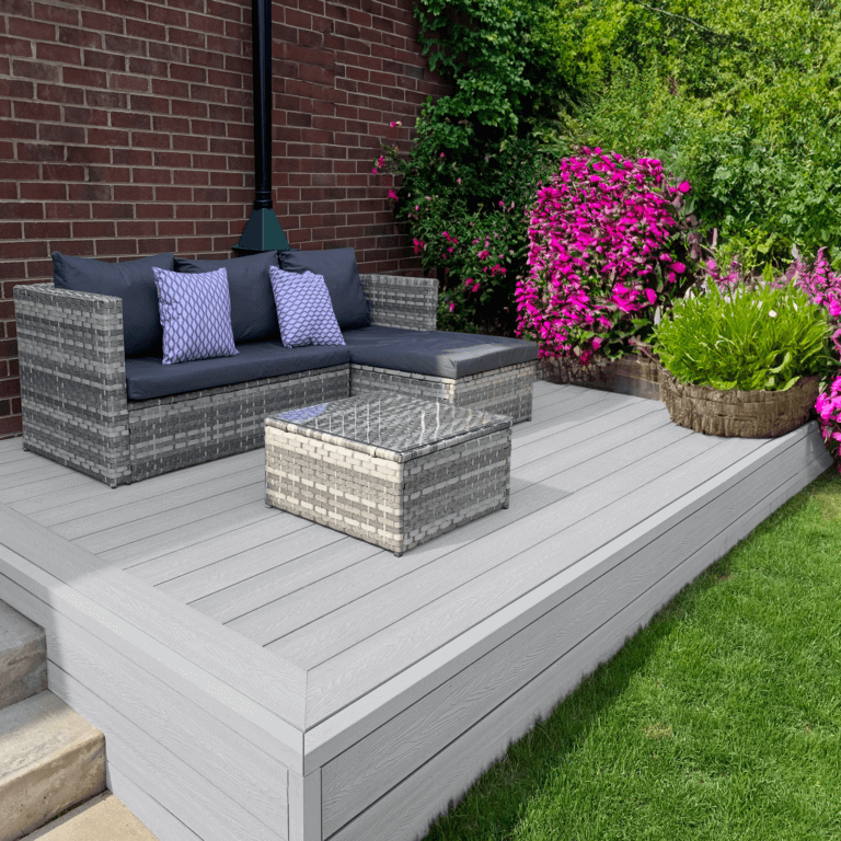 Stylish outdoor space featuring light grey composite decking, modern furniture, and colorful flowers.