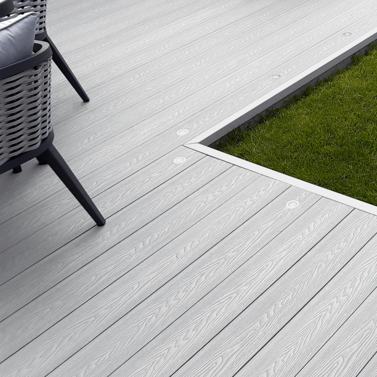 Light grey composite decking board with woodgrain texture, modern outdoor space, patio furniture, and grass border.