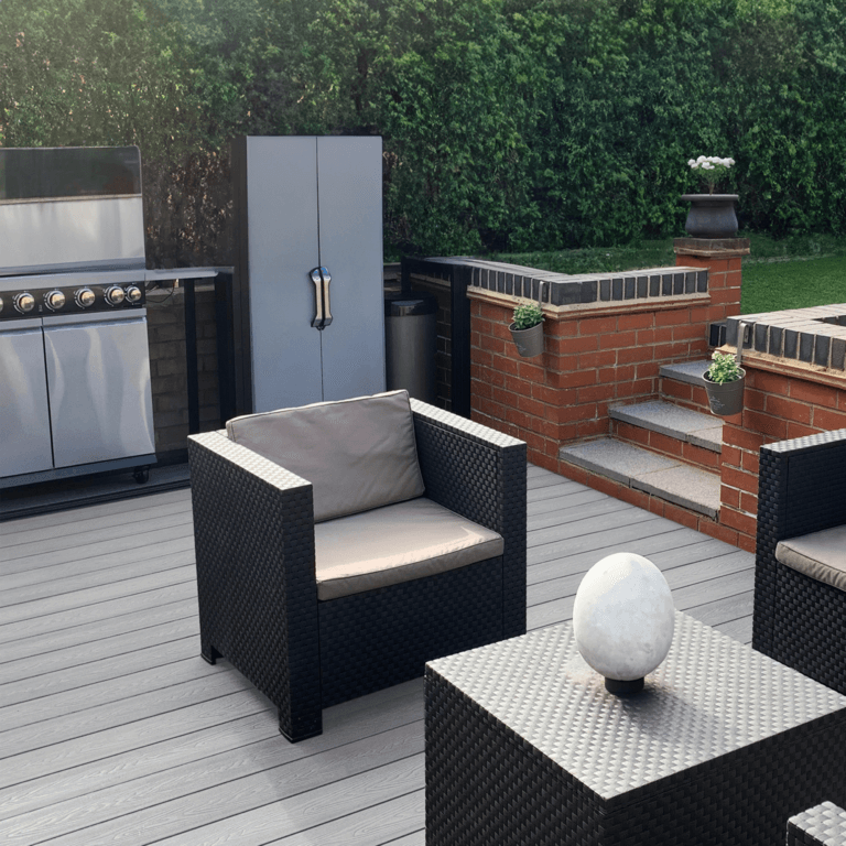 Outdoor lounging area featuring light grey composite decking, modern chairs, and a grill, enhancing your backyard space.