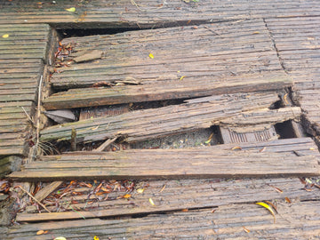 Severely damaged wooden decking boards requiring replacement