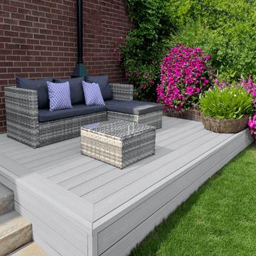 Light grey composite deck with garden sofa and flowering plants